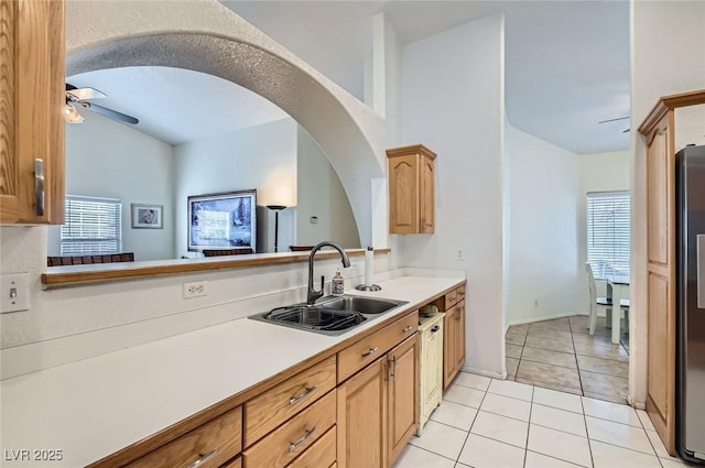 kitchen with light tile patterned floors, ceiling fan, freestanding refrigerator, light countertops, and a sink