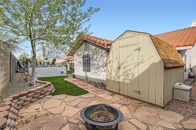 back of house featuring a tile roof, a fenced backyard, an outbuilding, a patio area, and a shed