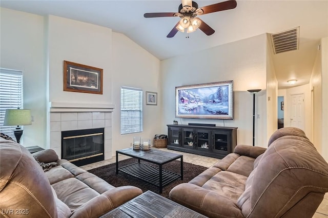 tiled living area featuring lofted ceiling, ceiling fan, a fireplace, and visible vents