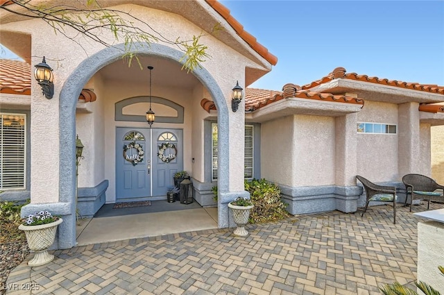 view of exterior entry featuring stucco siding and a tiled roof