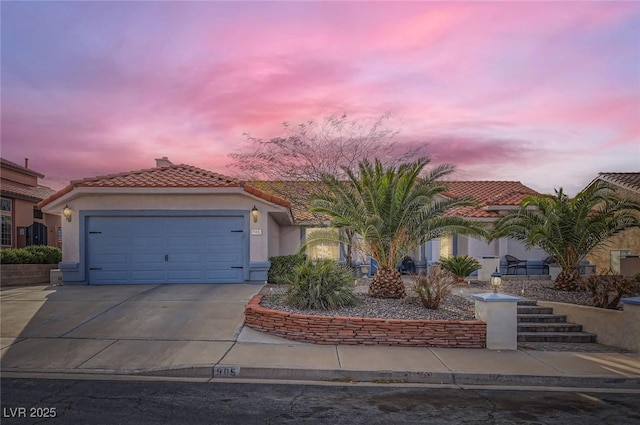 mediterranean / spanish-style house with a garage, a tile roof, driveway, and stucco siding