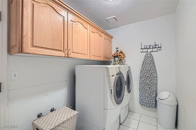 laundry area with washer and dryer, cabinet space, a textured ceiling, and light tile patterned floors