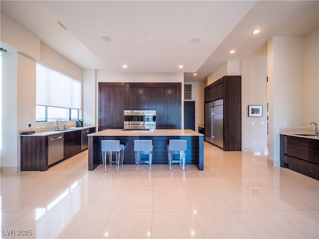 kitchen featuring stainless steel appliances, a breakfast bar, a sink, and modern cabinets