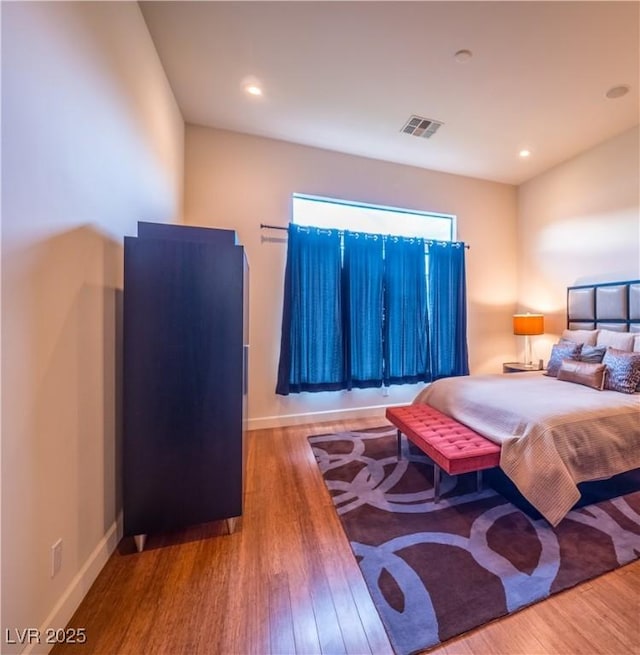 bedroom with recessed lighting, wood finished floors, visible vents, and baseboards