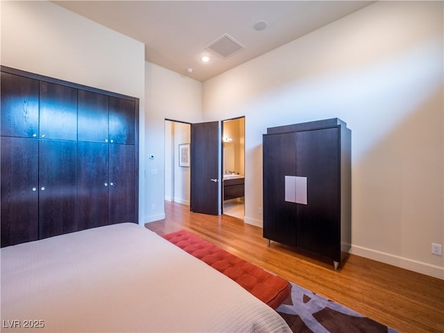 unfurnished bedroom featuring visible vents, connected bathroom, baseboards, and wood finished floors