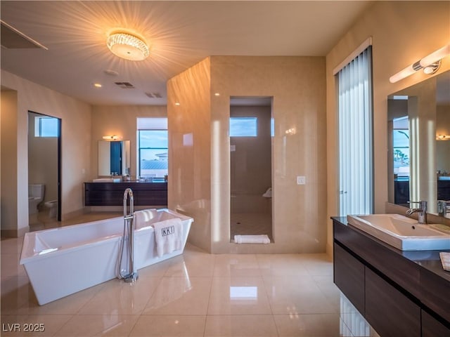 full bath featuring visible vents, a freestanding bath, toilet, vanity, and tile patterned floors