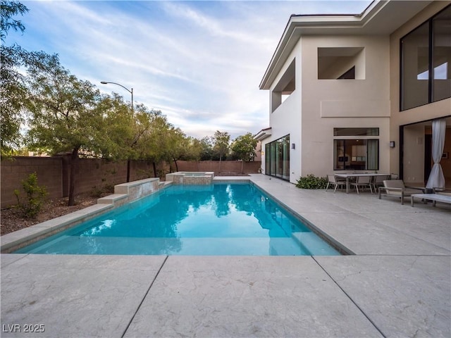 view of swimming pool with a fenced backyard, a pool with connected hot tub, and a patio