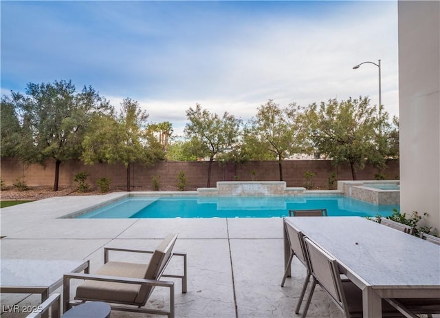 view of pool with a patio area, a fenced backyard, and a pool with connected hot tub