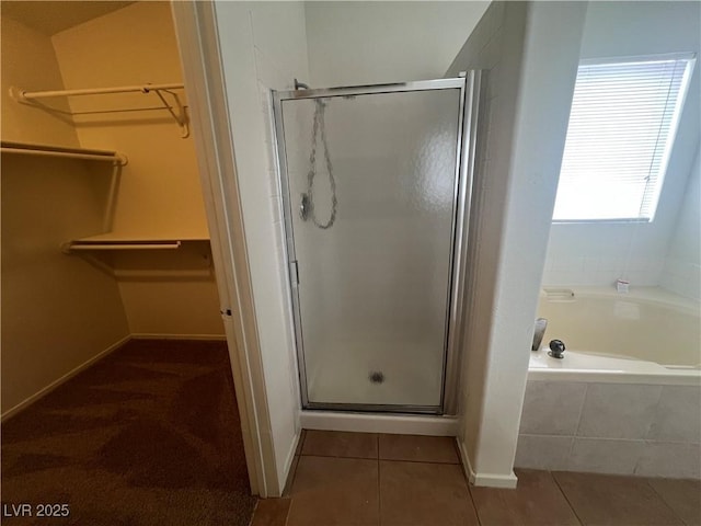 bathroom with tile patterned floors, a shower stall, a bath, and a spacious closet