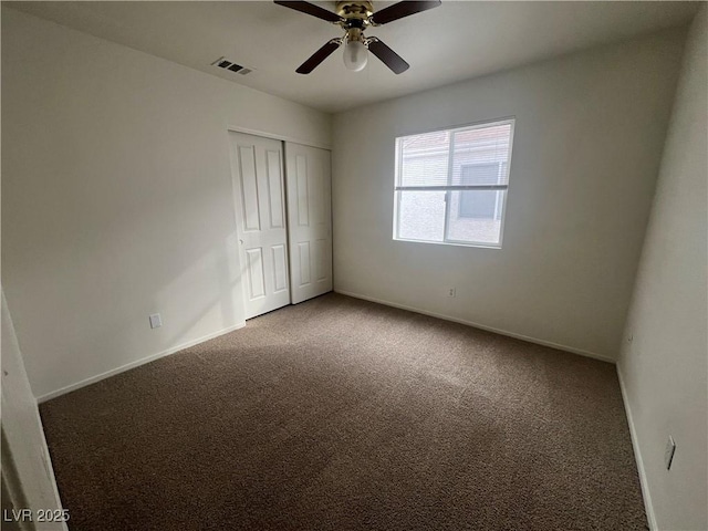 carpeted empty room with baseboards, visible vents, and a ceiling fan