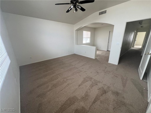 unfurnished room with visible vents, arched walkways, a ceiling fan, vaulted ceiling, and carpet floors