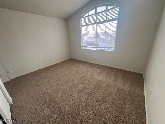 carpeted spare room with vaulted ceiling and baseboards