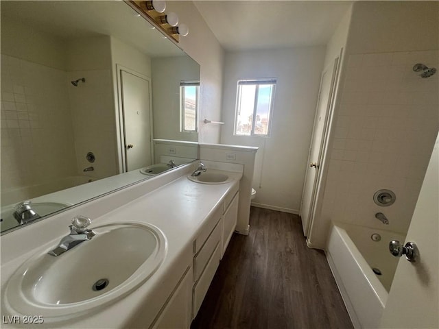 full bath with shower / tub combination, a sink, toilet, and wood finished floors