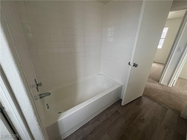 bathroom with washtub / shower combination and wood finished floors