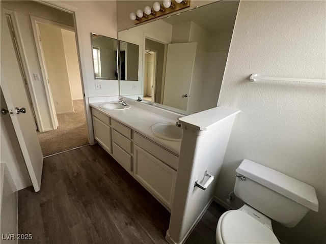 full bathroom featuring double vanity, wood finished floors, a sink, and toilet