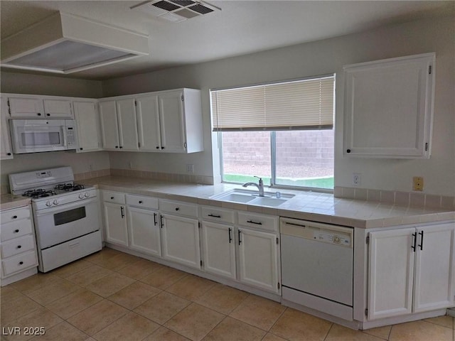 kitchen with tile countertops, visible vents, white cabinetry, a sink, and white appliances