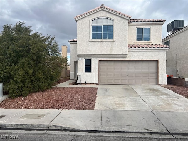 mediterranean / spanish house with central air condition unit, a garage, a tiled roof, driveway, and stucco siding