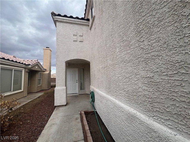 doorway to property featuring a tile roof and stucco siding