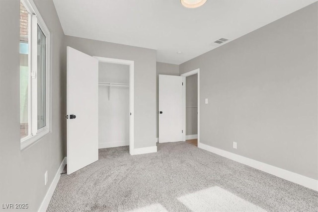 unfurnished bedroom featuring multiple windows, carpet, visible vents, and baseboards