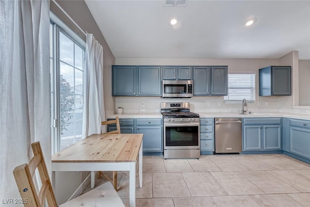 kitchen featuring a sink, appliances with stainless steel finishes, tile counters, and recessed lighting