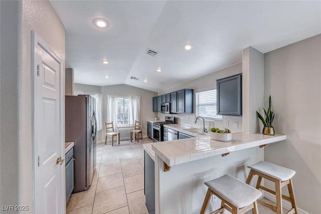 kitchen with stainless steel appliances, visible vents, a sink, a peninsula, and a kitchen bar