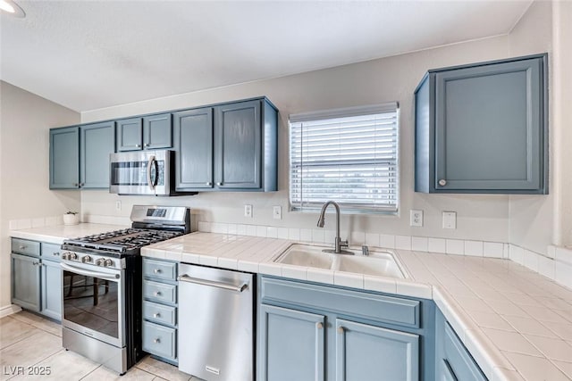 kitchen featuring appliances with stainless steel finishes, light tile patterned flooring, and a sink