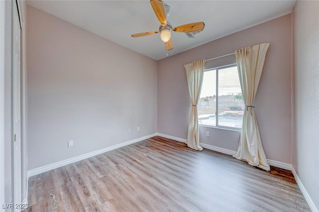 empty room featuring a ceiling fan, baseboards, and wood finished floors