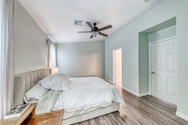 bedroom with a ceiling fan, baseboards, visible vents, and wood finished floors