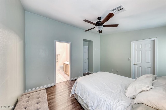 bedroom featuring dark wood-style flooring, visible vents, ensuite bathroom, a ceiling fan, and baseboards