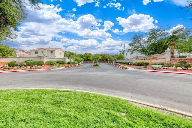 view of street with sidewalks, a gated entry, and curbs