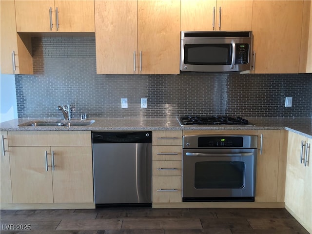 kitchen with light stone countertops, decorative backsplash, stainless steel appliances, and a sink