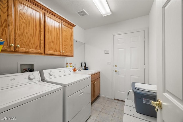 washroom featuring light tile patterned flooring, washing machine and dryer, a sink, visible vents, and cabinet space