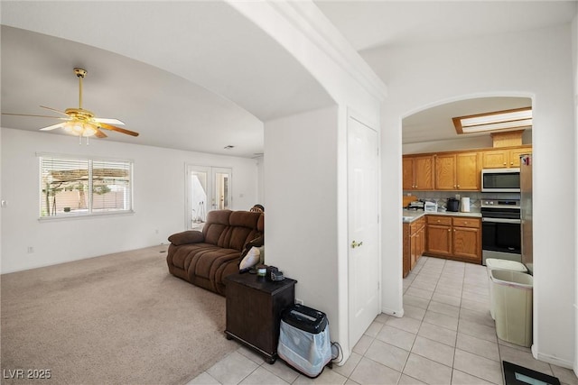 living area featuring light carpet, light tile patterned floors, and a ceiling fan