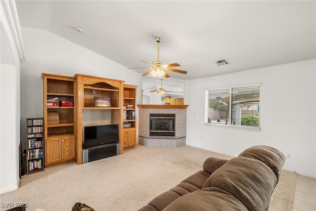 living area with visible vents, light colored carpet, ceiling fan, vaulted ceiling, and a fireplace