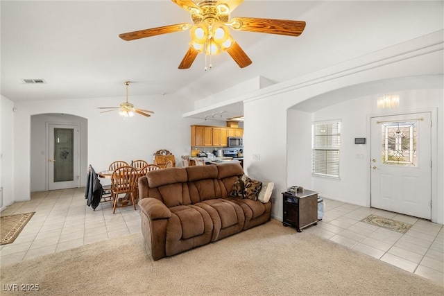 living room with light carpet, light tile patterned floors, visible vents, and arched walkways