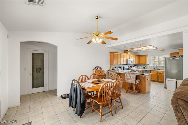 dining room featuring arched walkways, ceiling fan, light tile patterned flooring, and visible vents