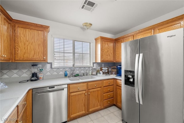 kitchen with appliances with stainless steel finishes, a sink, visible vents, and decorative backsplash