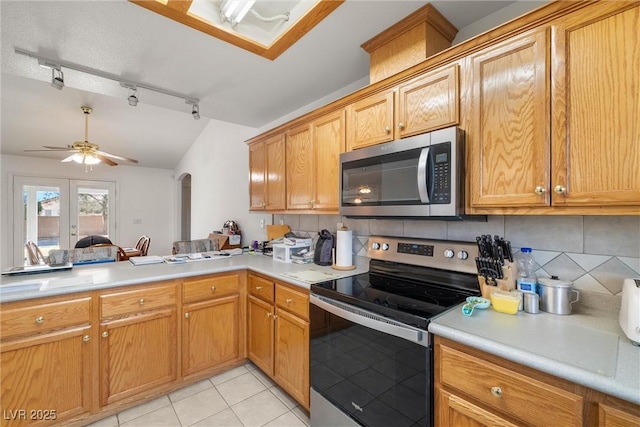 kitchen with arched walkways, stainless steel appliances, ceiling fan, and decorative backsplash