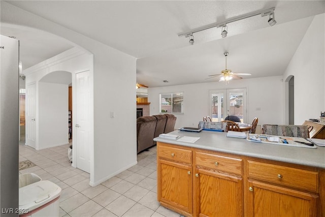 kitchen featuring arched walkways, open floor plan, vaulted ceiling, light countertops, and a fireplace