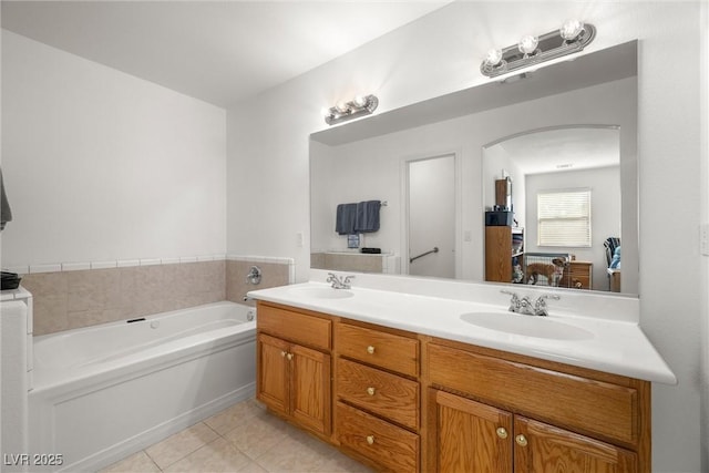 ensuite bathroom featuring connected bathroom, a garden tub, a sink, and tile patterned floors