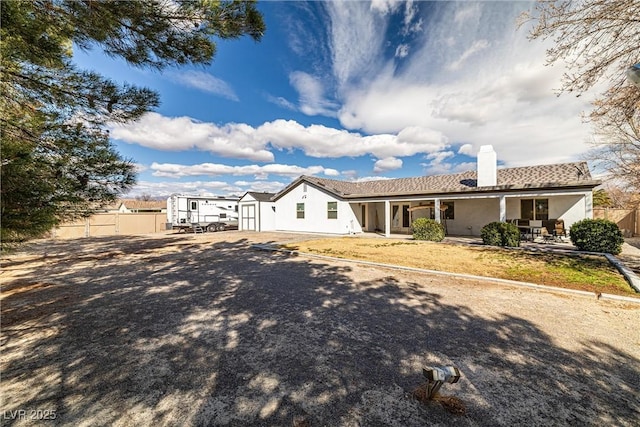 back of house with a patio, a chimney, an outbuilding, a storage unit, and fence