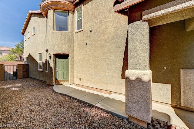 back of house with fence, a gate, and stucco siding