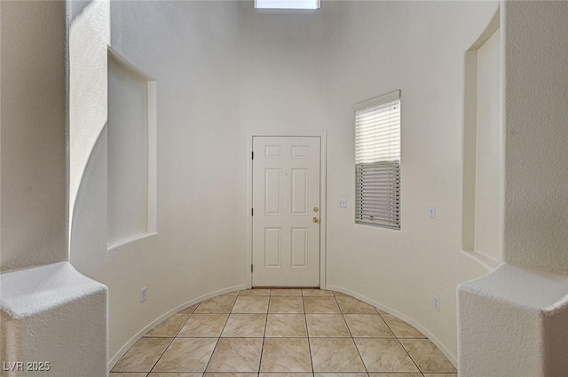 foyer featuring light tile patterned floors, a high ceiling, and baseboards