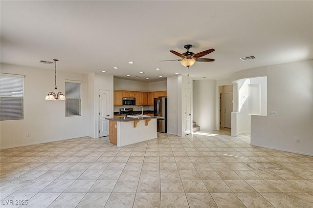 kitchen with open floor plan, visible vents, ceiling fan with notable chandelier, and freestanding refrigerator