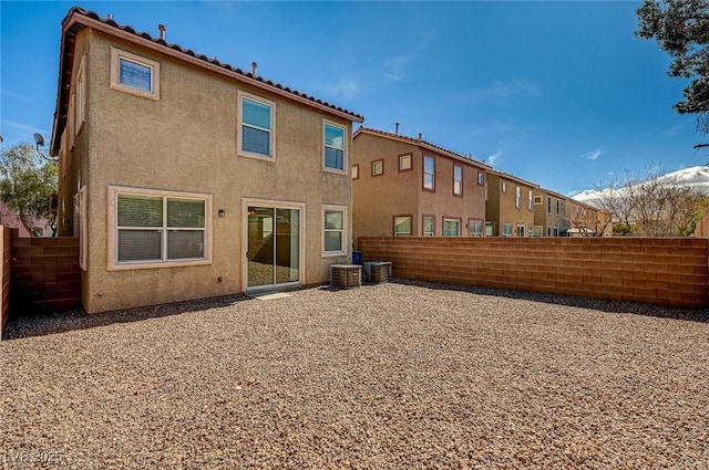 rear view of house with central air condition unit, a fenced backyard, and stucco siding