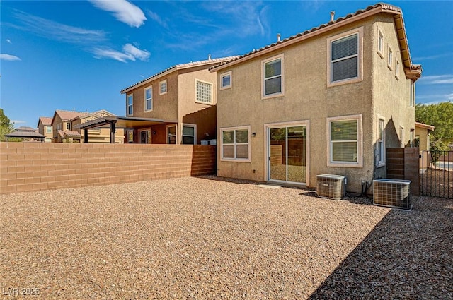 rear view of property with fence, central AC unit, and stucco siding