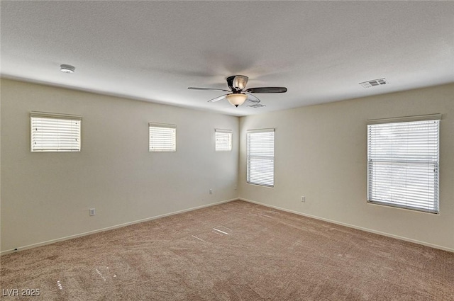 empty room featuring baseboards, visible vents, light colored carpet, ceiling fan, and a textured ceiling