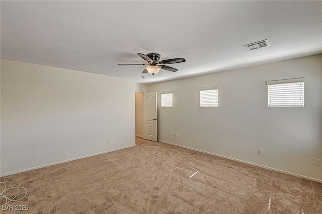 spare room featuring light carpet, ceiling fan, visible vents, and baseboards