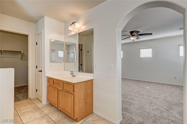 bathroom with ceiling fan, visible vents, vanity, tile patterned floors, and a walk in closet