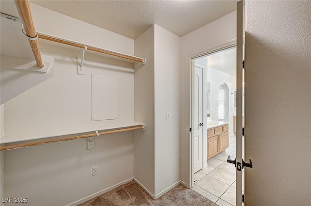 spacious closet with light carpet and arched walkways